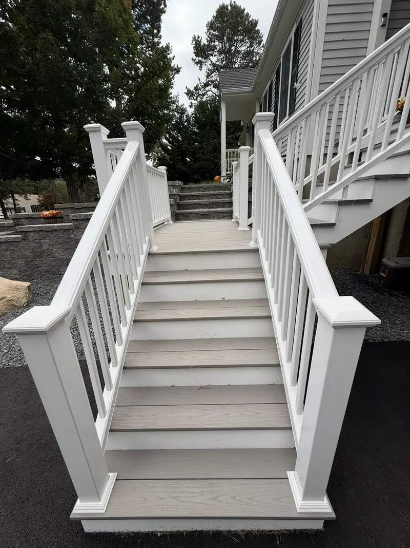 Composite deck stairs with a white railing leading up to a house